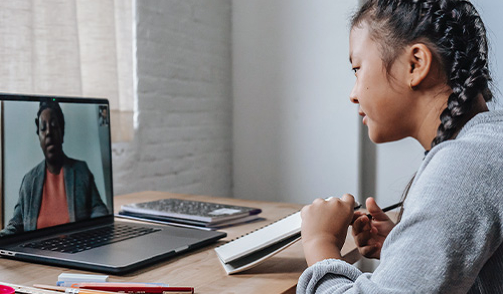 Middle school student watching an online class with her laptop at home