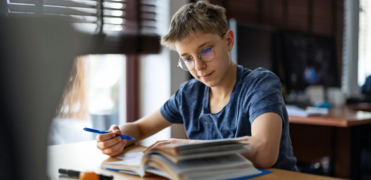 Middle school student reading a book and taking notes